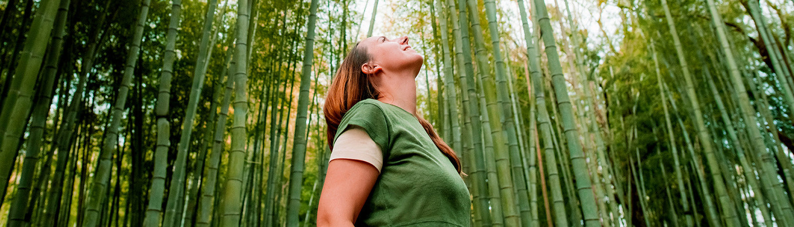 Woman looking up to the sky in a forest.
