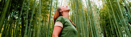 Woman looking up to the sky in a forest.