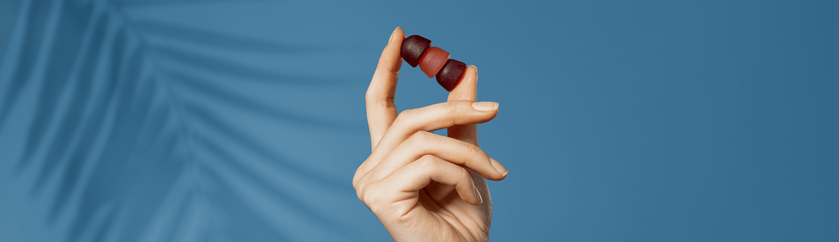 A hand holding three gummies.