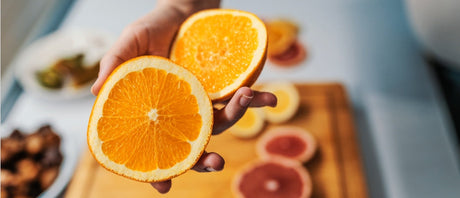 A hand holding two halves of an orange.