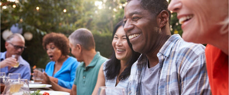 A group of people sitting at a table outside smiling and laughing.