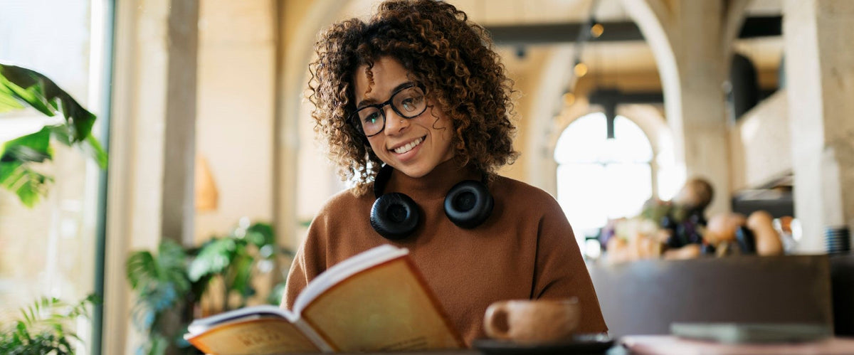 woman with headphones reading a book