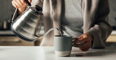 A woman pouring water into a cup.
